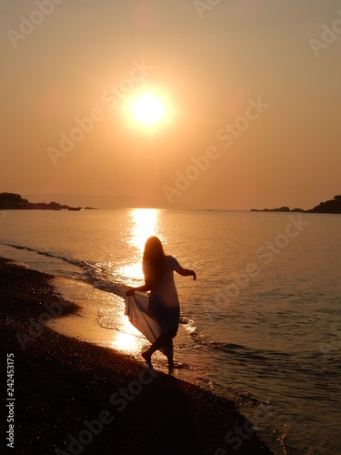 Ragazza cammina sul mare al tramonto photo