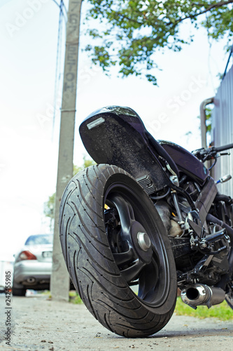 Cropped close up shot of beautiful and custom made motorcycle parked on the street photo