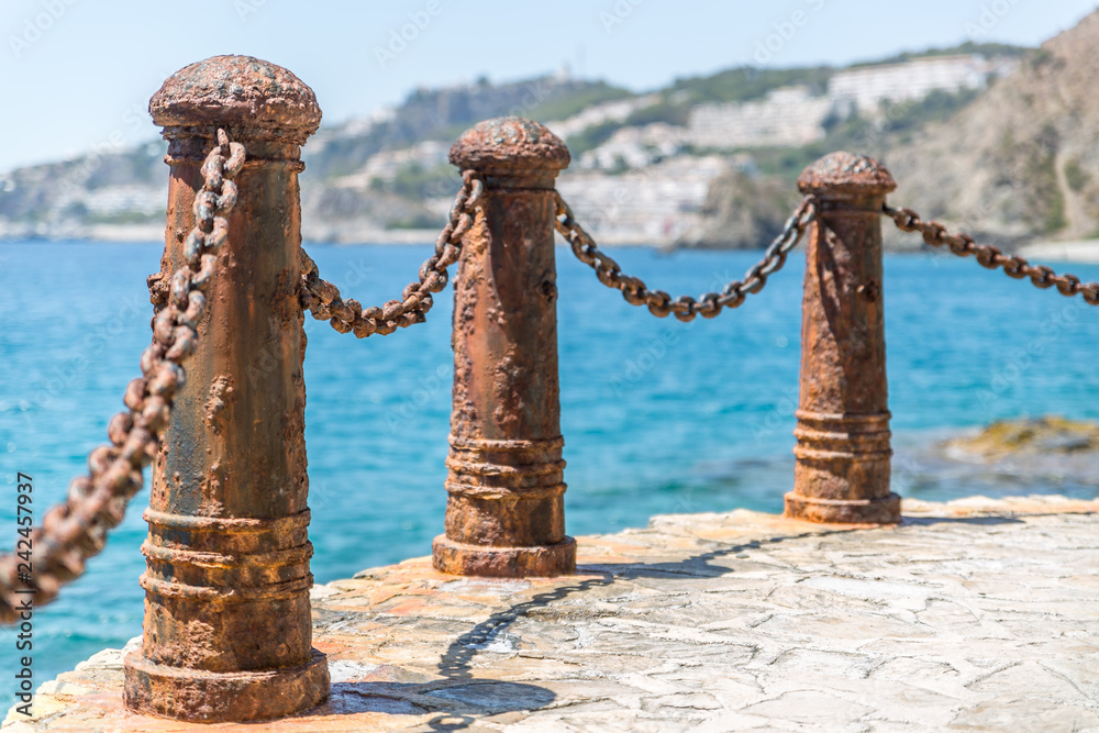 Obraz premium Metal bollards and chains to make a barrier on a beautiful beach in southern Spain, Almunecar