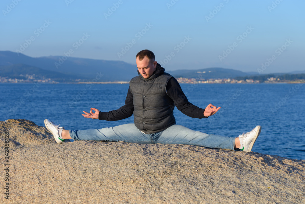 young man doing yoga sitting in a twine on a rock young man doing yoga sitting in a twine on a rock