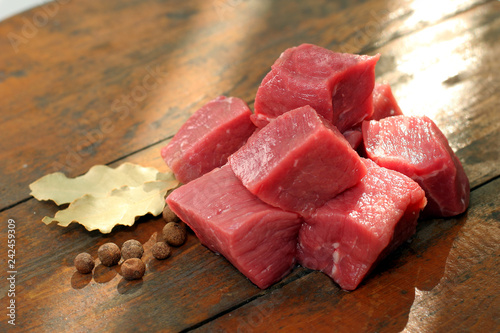 Mięso na gulasz z szynki wieprzowej. Kompozycja mięsa z przyprawami na drewnianej desce.