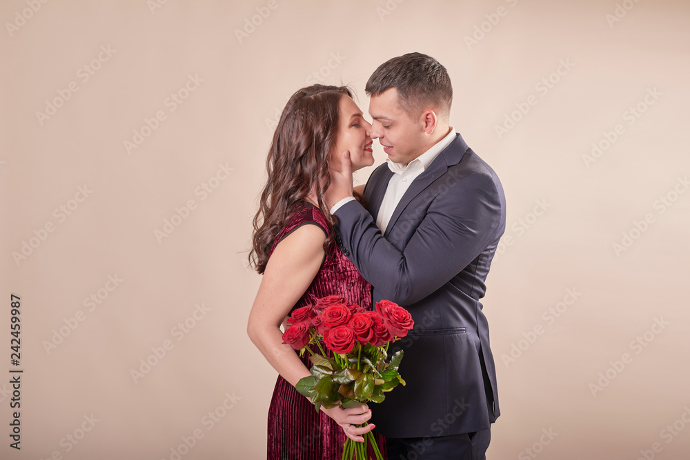 young married couple with a bouquet of red roses on a beige background on February 14 in Valentine's Day young married couple with a bouquet of red roses on a beige background on February 14 in Valentine's Day