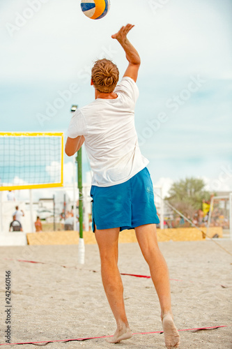 Volleyball beach player is a male athlete volleyball player getting ready to serve the ball on the beach.