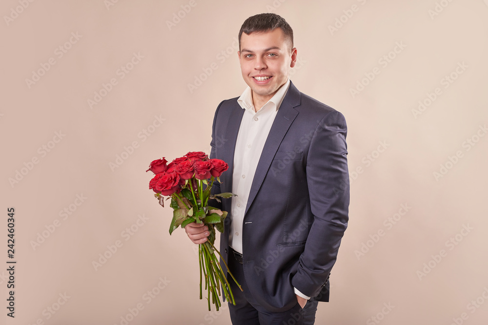 young attractive man with red roses on a beige background on Valentine's Day February 14 young attractive man with red roses on a beige background on Valentine's Day February 14