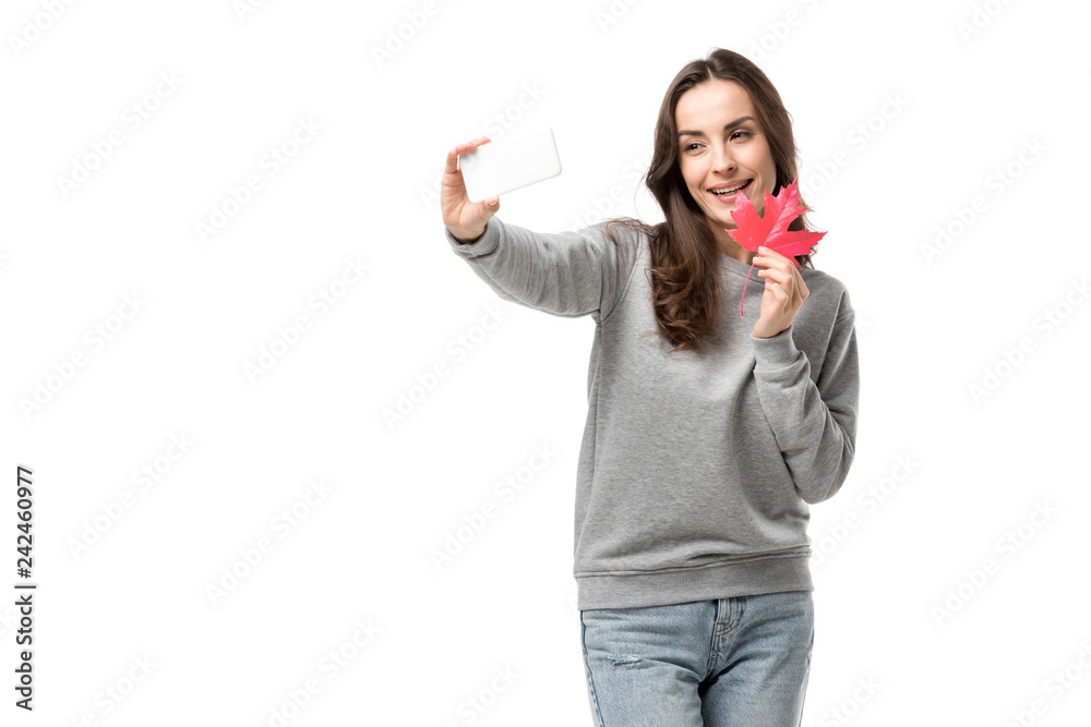 smiling woman in casual clothes holding maple leaf and taking selfie on smartphone isolated on white smiling woman in casual clothes holding maple leaf and taking selfie on smartphone isolated on white