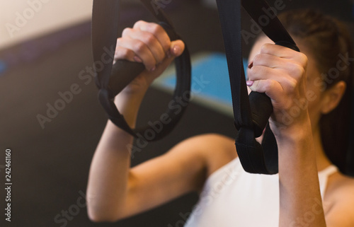 Girl holding strap during suspension training in the gym