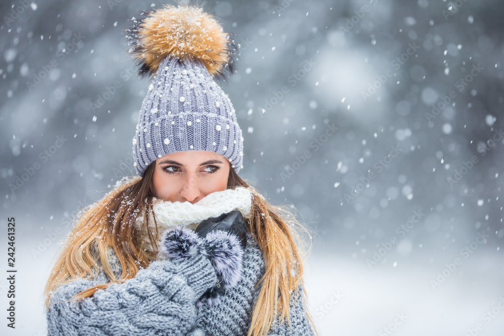 Portrait of young beautiful woman in winter clothes and strong snowing. - obrazy, fototapety, plakaty 