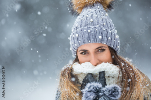 Portrait of young beautiful woman in winter clothes and strong snowing.