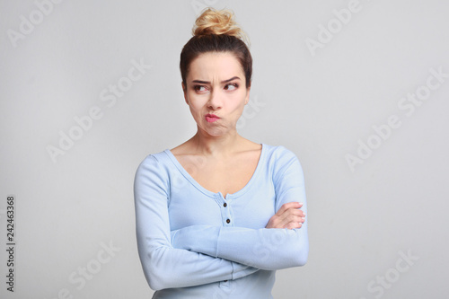 Confused woman standing with crossed arms and looking aside