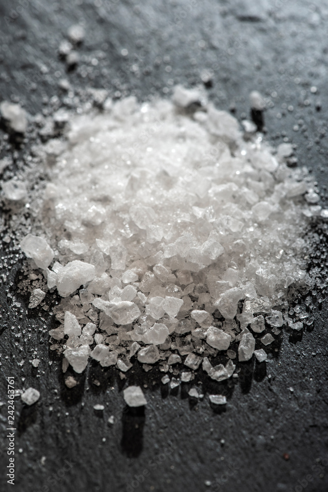 White salt crushed on dark stone background. Close-up Big pieces of salt. White salt crushed on dark stone background. Close-up Big pieces of salt.