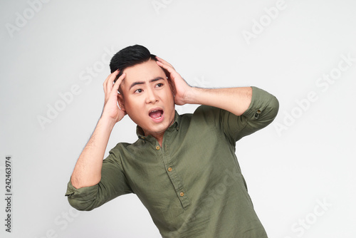 Oh no! Portrait of surprised, shocked man with stubble and wide opened mouth and eyes in checkered shirt touching head with two hands isolated on grey background