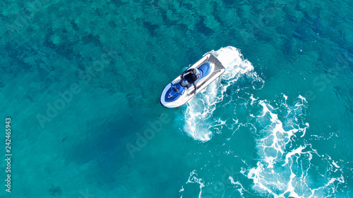 Aerial top view of jet ski cruising in low speed in mediterranean emerald clear waters