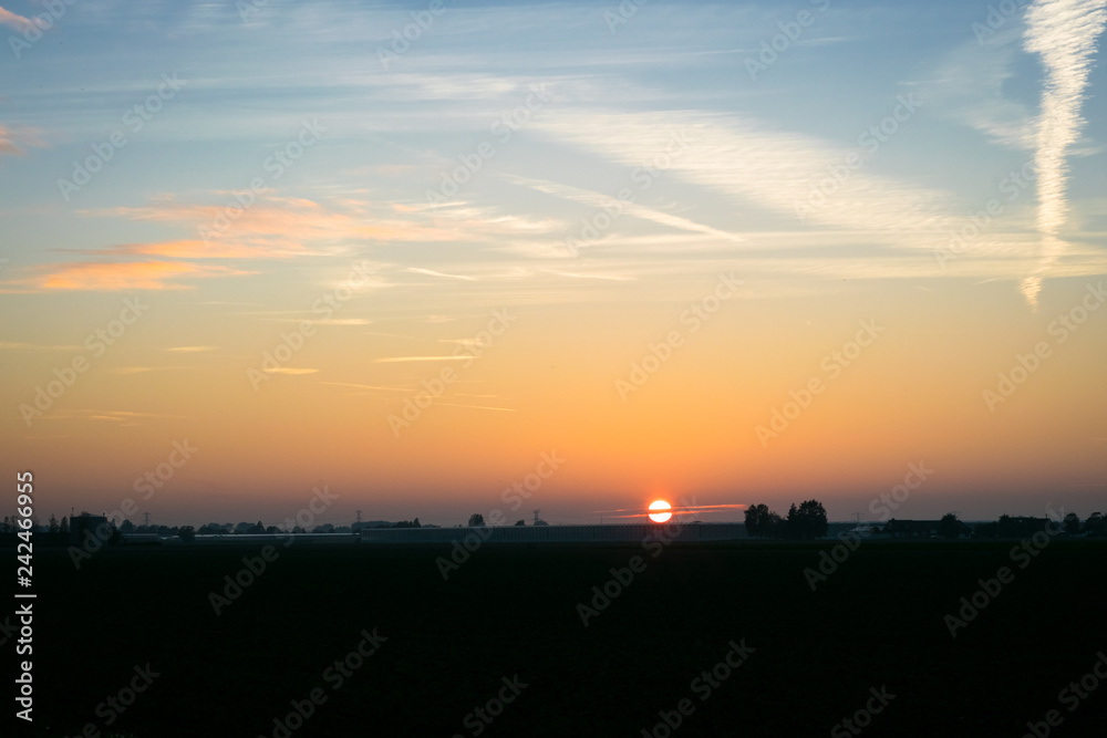 The sun sets over the dutch countryside.  Photograph was taken on an autumn day in the Green Heart of Holland: the area between the cities of Amsterdam, Rotterdam, The Hague and Utrecht.
