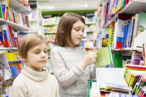 Two girls choosing books in bookstore for school