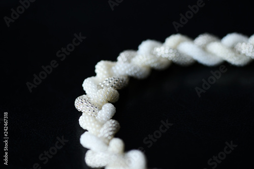 Beaded necklace in the shape of braid on a dark background close up © Talulla