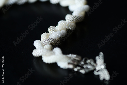 Beaded necklace in the shape of braid on a dark background close up
