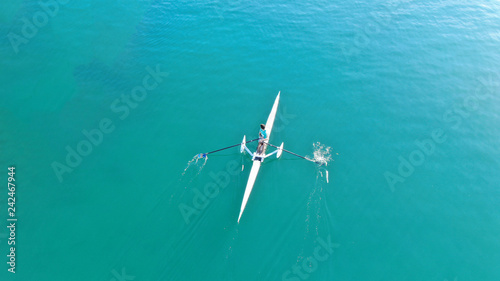 Aerial drone bird's eye view of sport canoe operated by young fit man in turquoise clear waters