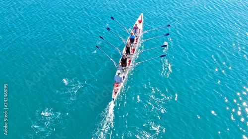 Aerial drone bird's eye view of sport canoe operated by team of young women in emerald clear sea © aerial-drone