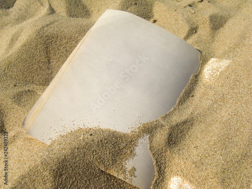 Empty yellowed pages of an old vintage notebook covered with small grains of sand and forgotten somewhere on a sunny beach by the sea.