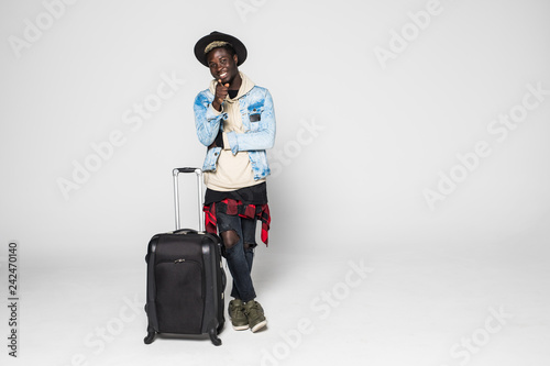 Full length of a african tourist walking and pulling a suitcase isolated on white background