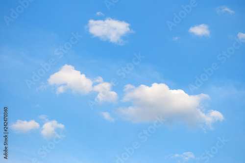 White fluffy clouds with blue sky and sun light for background texture 