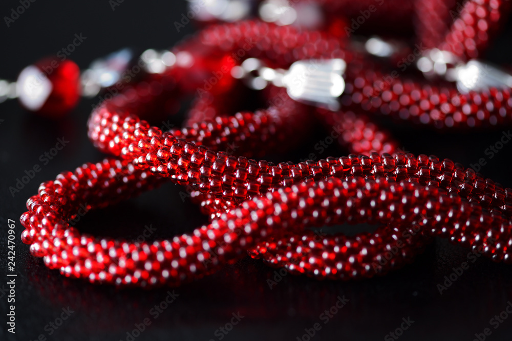 Lariat necklace red color with bead decoration on a dark background close up