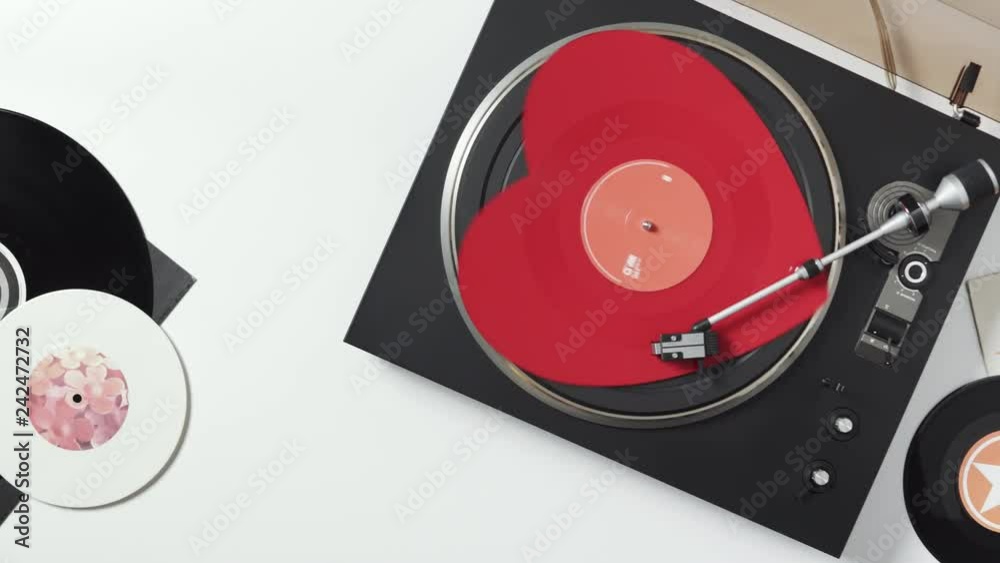 Side view of a  with a rotating red heart-shaped vinyl record with a stylus with a needle. Turntable. Loop