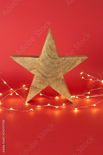 Weihnachtlicher Stern aus Holz und LIchterkette auf rotem Hintergrund