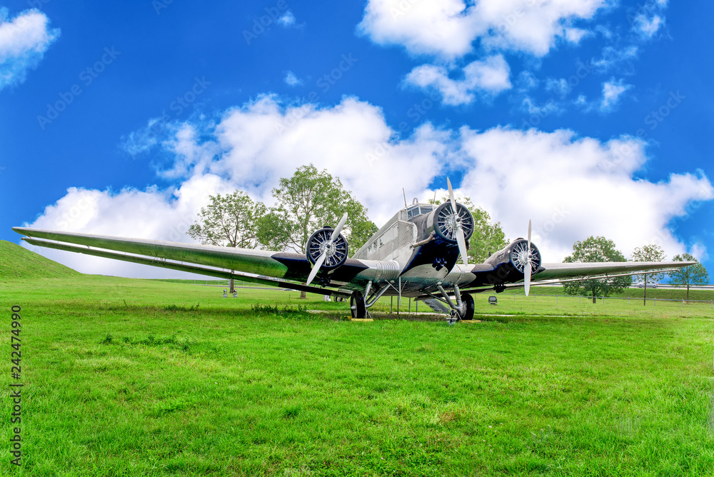 Big propeller airplane on green field in summer under blue cloudy sky. Big propeller airplane on green field in summer under blue cloudy sky.
