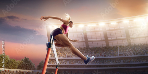 Female Track and field athlete jumps over the barrier at the running track in professional stadium