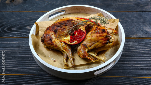 Fotografija roasted rabbit with pomegranate and rosemary on a paper on the old table