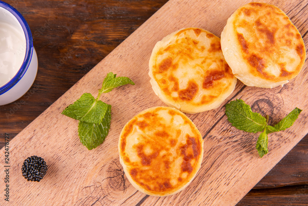 Cheesecakes, are served with sour cream and leaflets of mint Cheesecakes, are served with sour cream and leaflets of mint