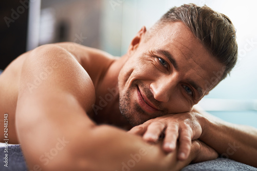 Принти на полотні Handsome young man lying on bed and expressing positive emotions