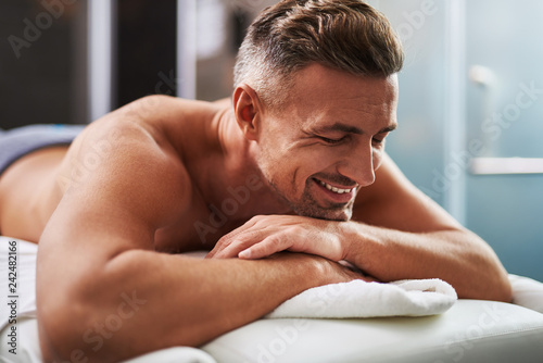 Handsome young man with closed eyes lying on massage table