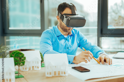 Attentive engineer smiling while working with virtual reality glasses