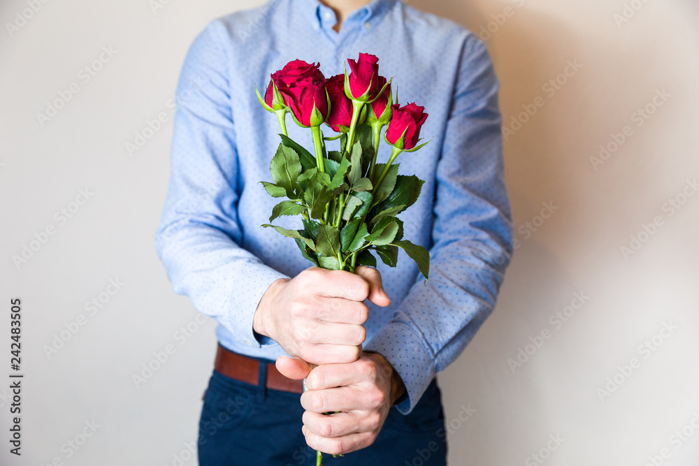 Handsome young man holding red rose bouquet, romantic Valentines day surprise, love,flowers.