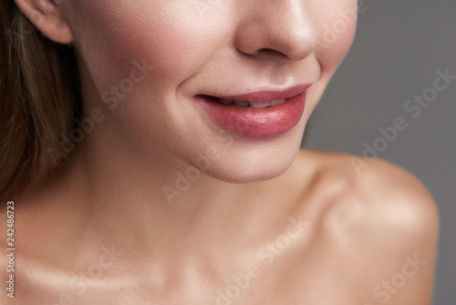 Joyful young lady with beautiful lips on gray background