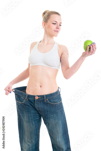 Sporty slim female model showing big pants and apple.