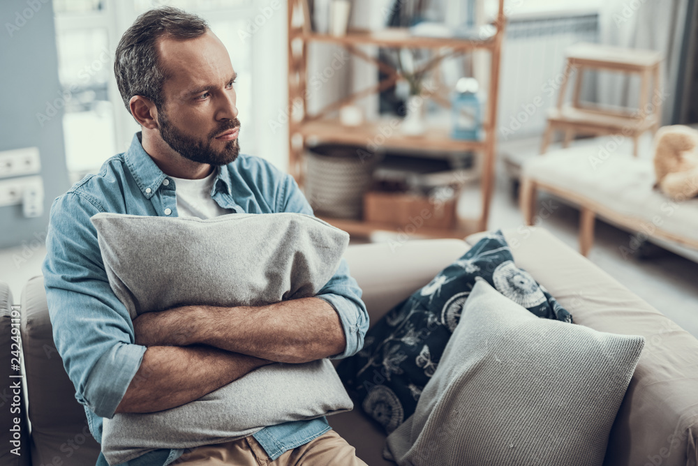 Worried man frowning while pressing pillow to his chest Stock Photo ...