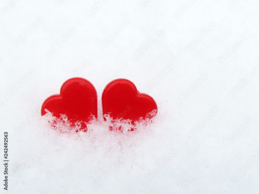 Two Valentine hearts in the snow, red symbols of love. Background for Valentines day greeting card, concept of romantic celebration