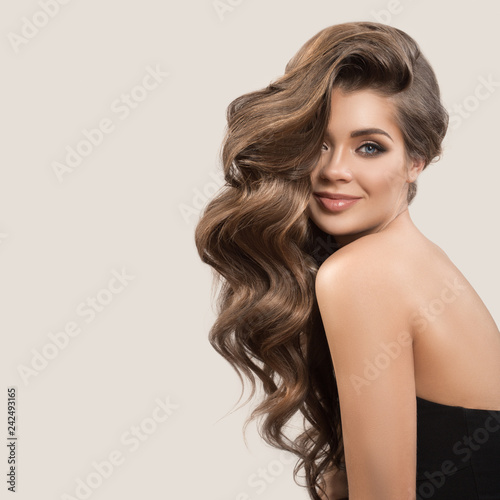 Portrait of beautiful cute woman with curly brown long hair. Gray background.