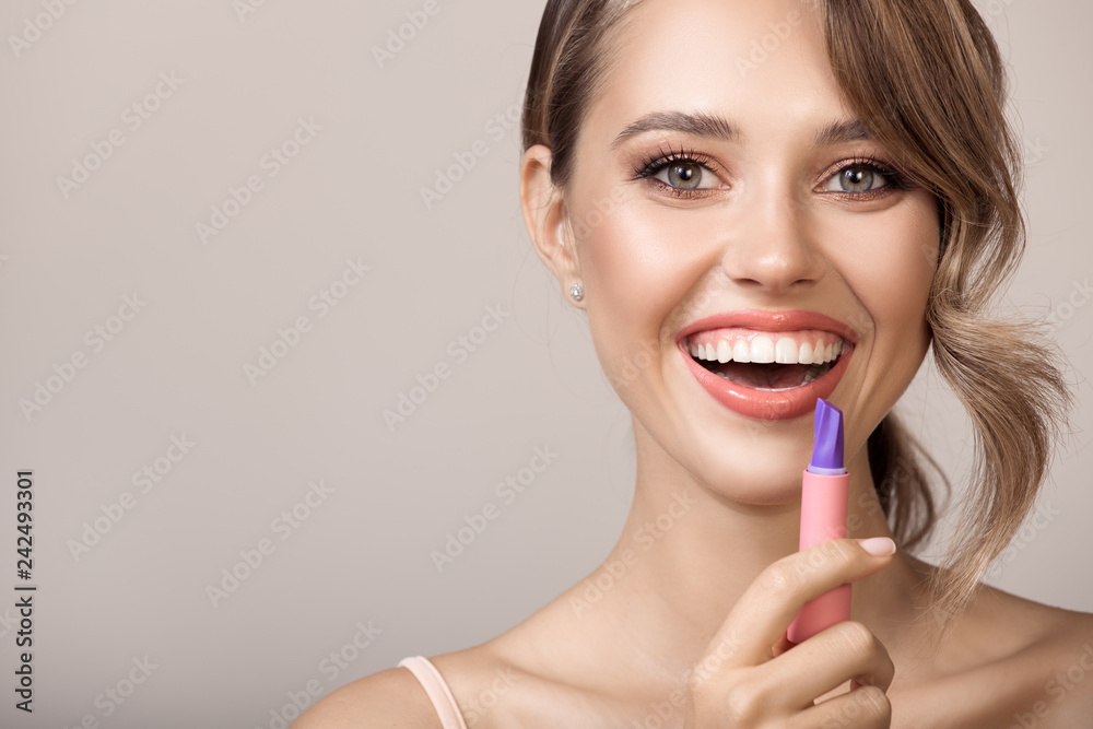Attractive smiling woman holding lipstick in hand. Attractive smiling woman holding lipstick in hand.