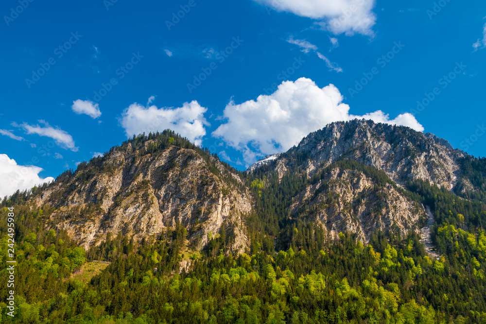 Magnificent view of the northwestern edge of the mountain range Ammergau Alps in Bavaria, Germany on a beautiful clear day with a blue sky; seen from the Alpsee, near Neuschwanstein Castle. Magnificent view of the northwestern edge of the mountain range Ammergau Alps in Bavaria, Germany on a beautiful clear day with a blue sky; seen from the Alpsee, near Neuschwanstein Castle.