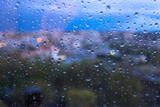 Raindrops on window glasses surface with blurred cityscape background