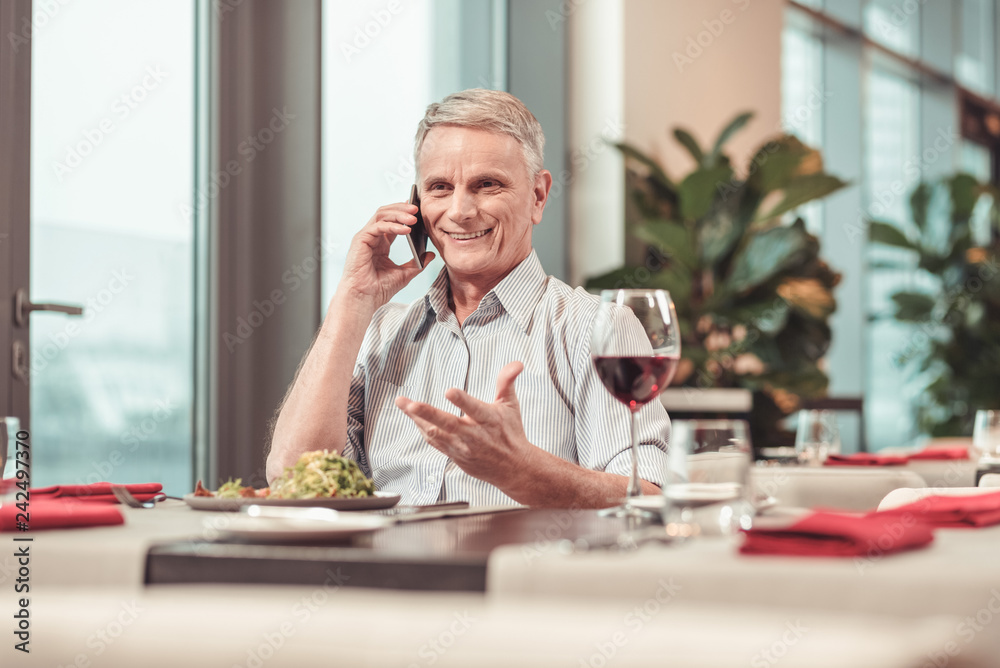 Joyful retired man speaking on the phone Joyful retired man speaking on the phone