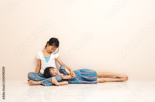 Little asian girl sitting with her old sister on floor at home. lovely relation between siblings.