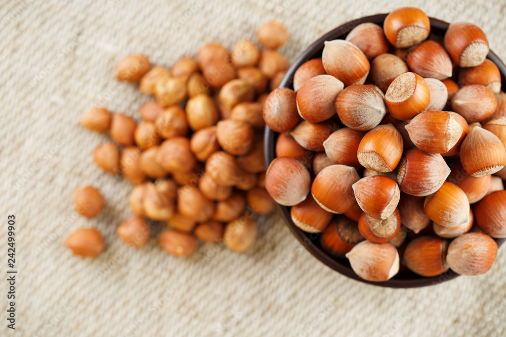 Peeled hazelnuts in a wooden, dark brown cup on a burlap cloth. Super Food, Raw. Peeled hazelnuts in a wooden, dark brown cup on a burlap cloth. Super Food, Raw.
