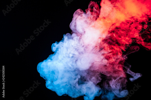 A cloud of isolated colored smoke exhaled from a vape: blue, red, orange, pink; on a dark background close up swirls in waves.
