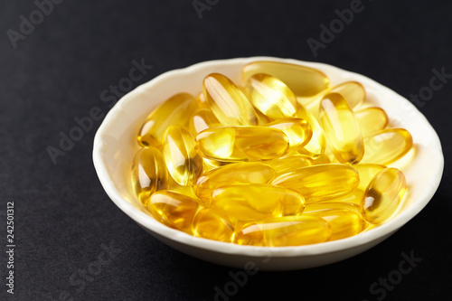 Fish oil capsules with omega 3 on black background. 