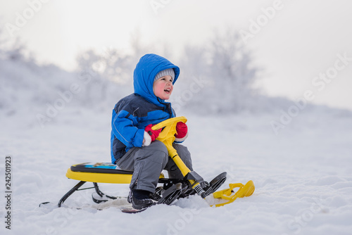 a small child is sitting on a snow scooter in winter